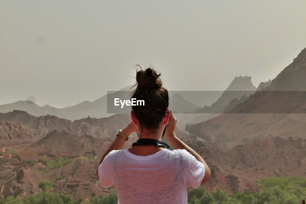 Rear view of woman photographing mountains