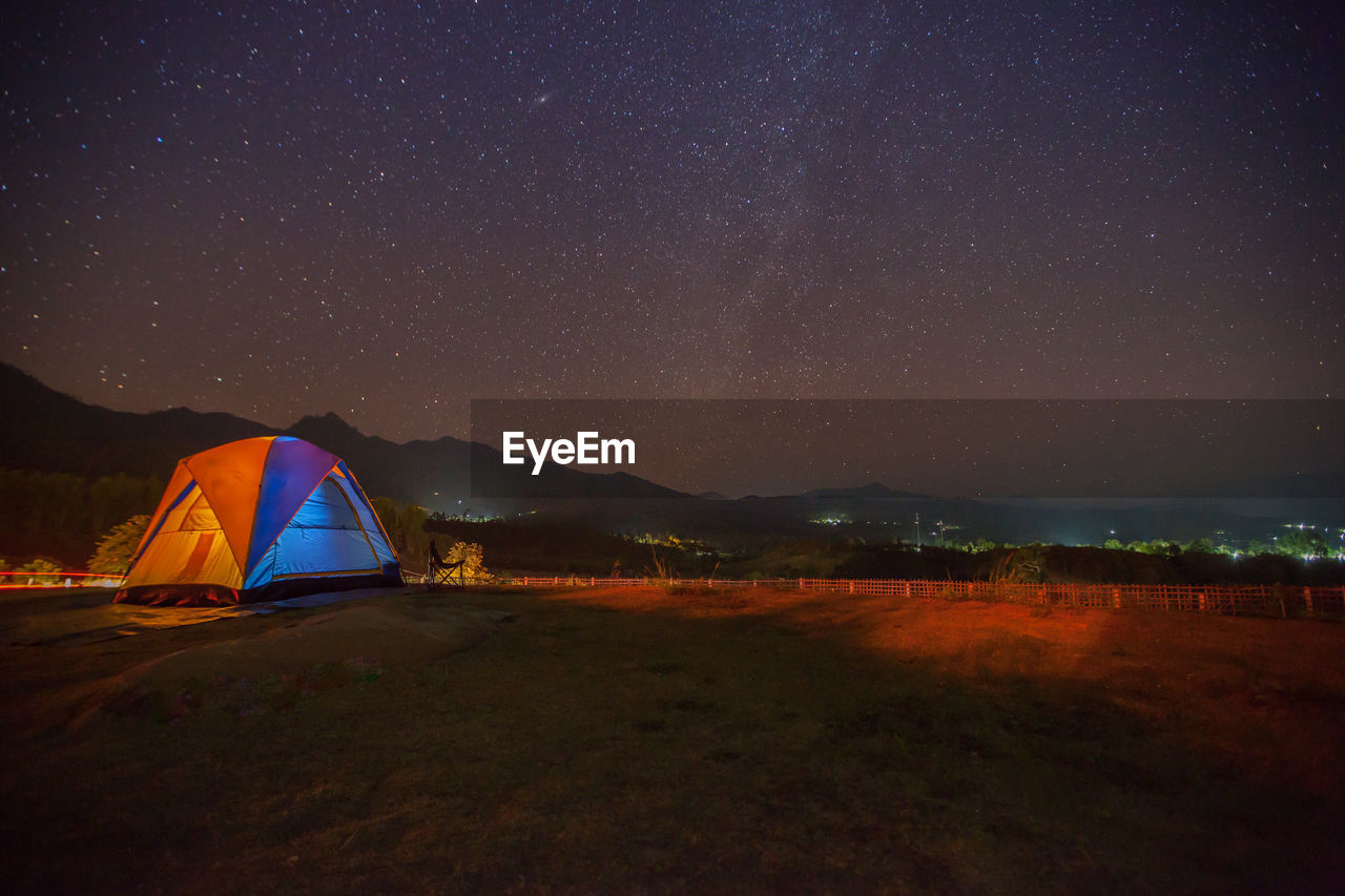 SCENIC VIEW OF ILLUMINATED FIELD AGAINST SKY