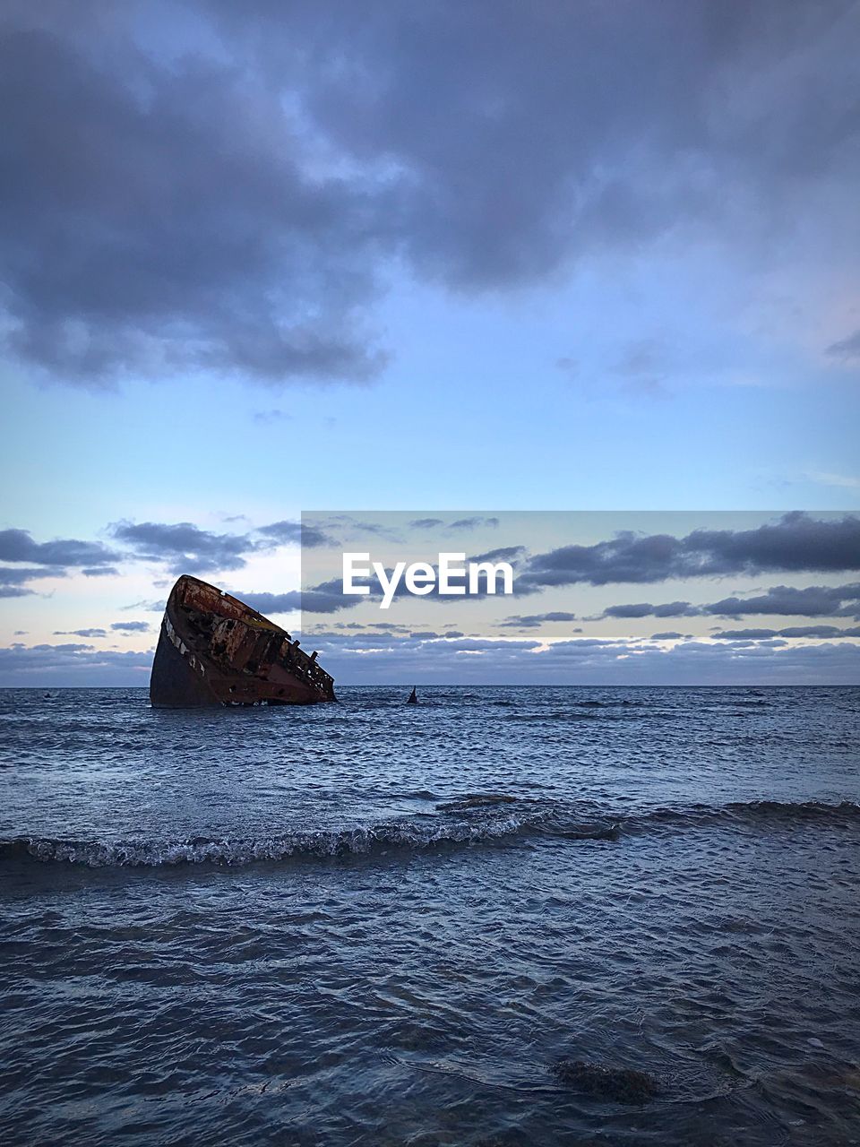 ABANDONED BOAT ON BEACH AGAINST SKY