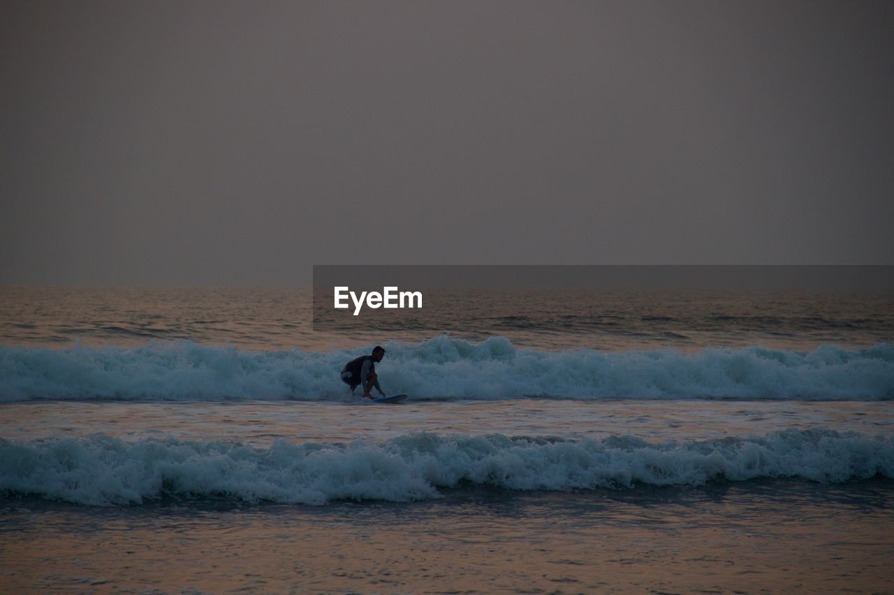 Man is serfing against clear sky during sunset in goa