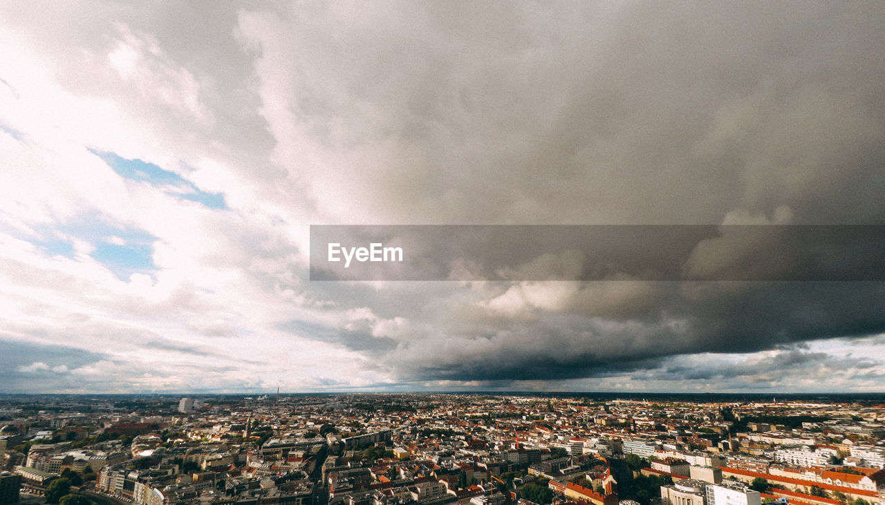 Aerial view of cityscape against cloudy sky