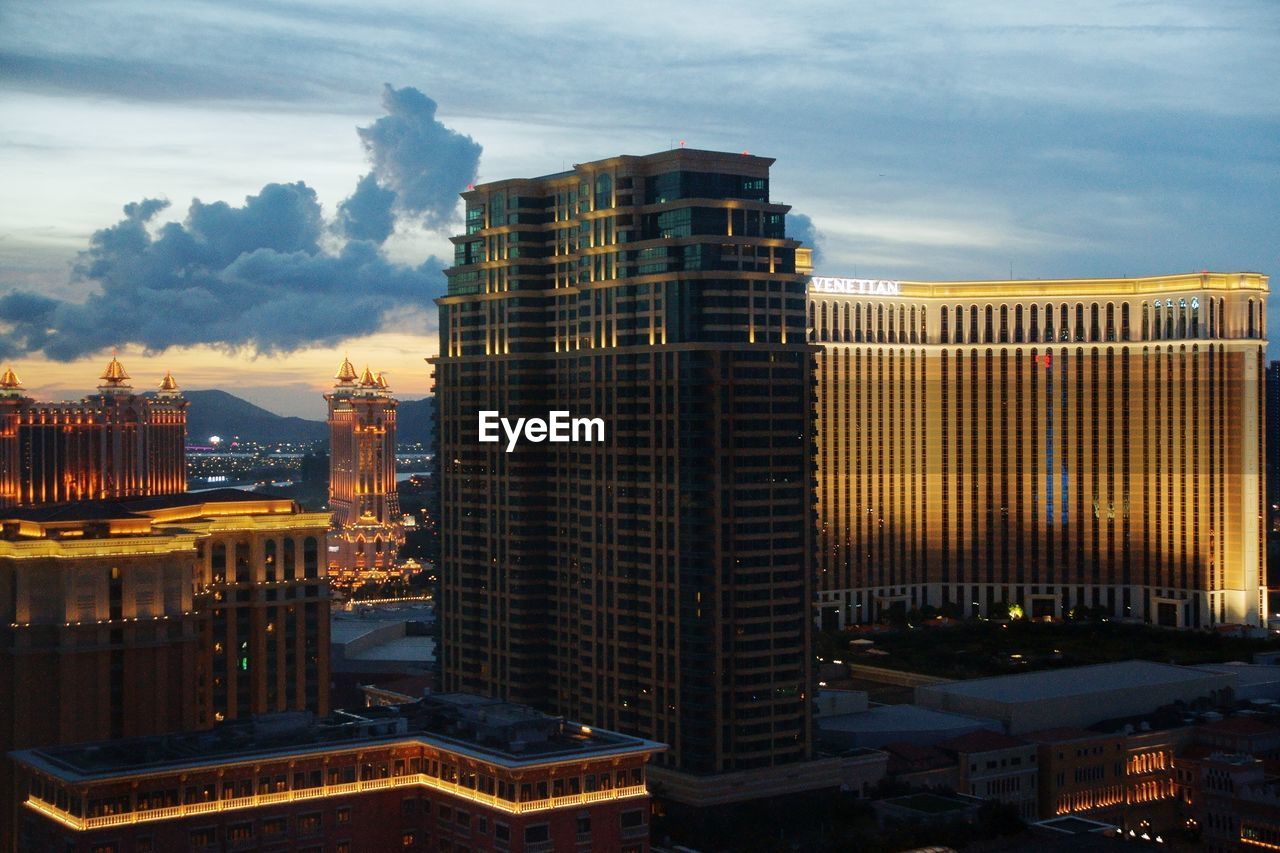 Illuminated buildings against sky during sunset in city