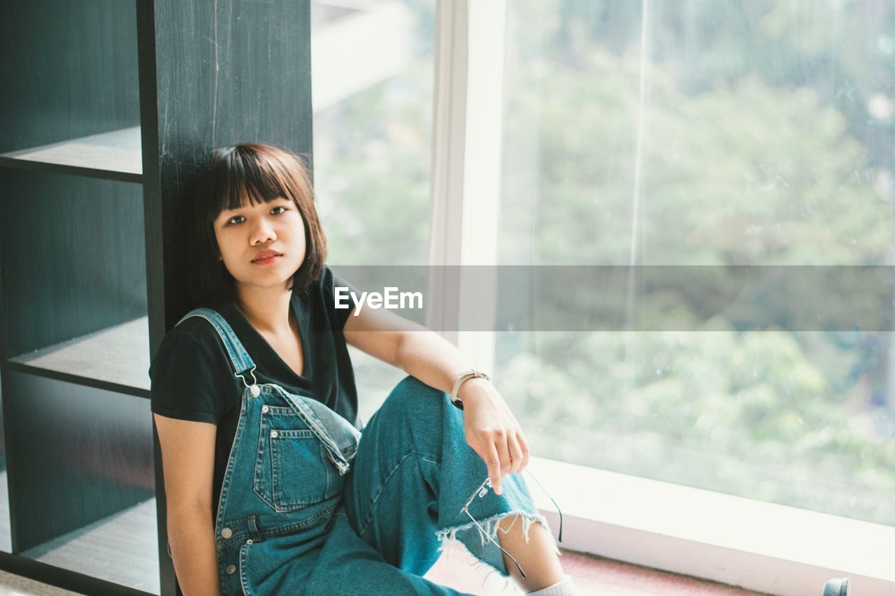 Portrait of young woman sitting by window