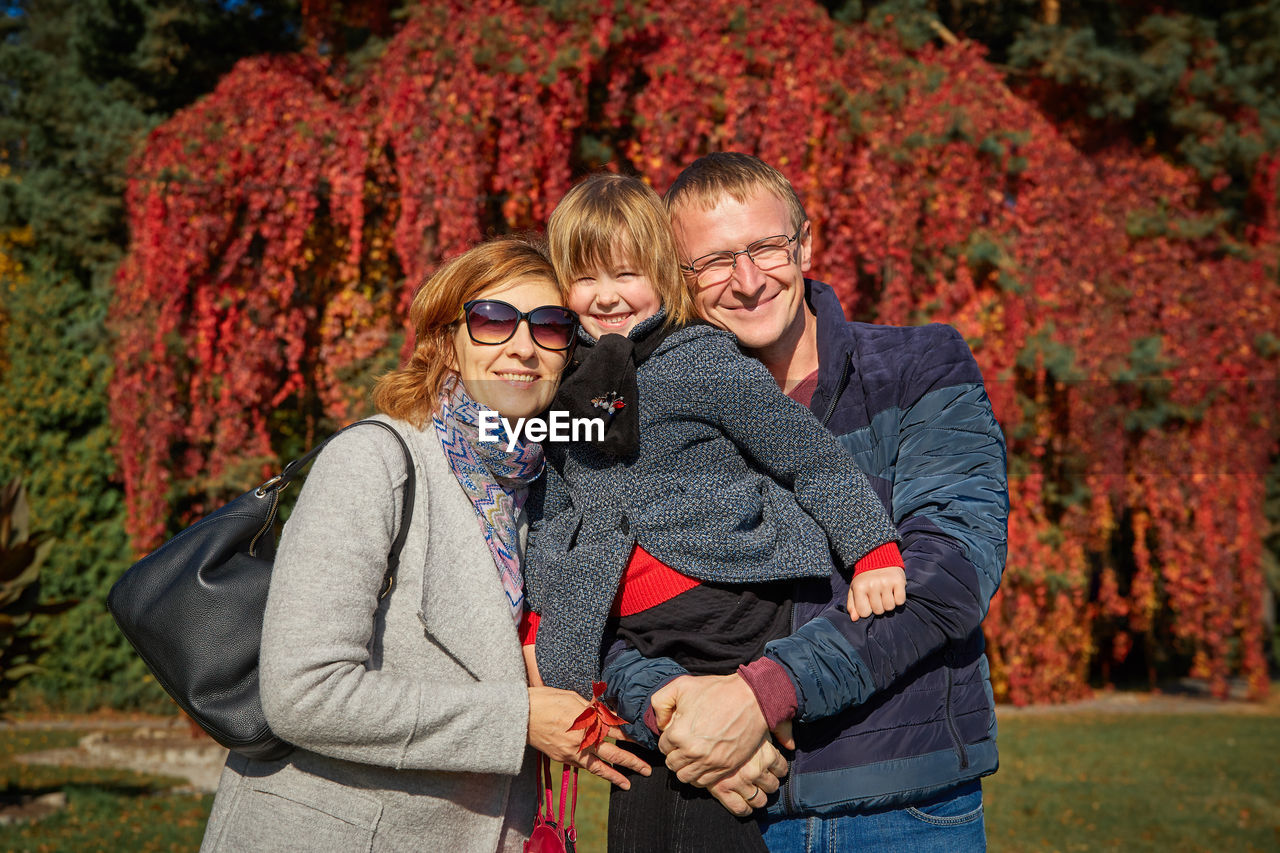 Portrait of parents standing with daughter at park during autumn