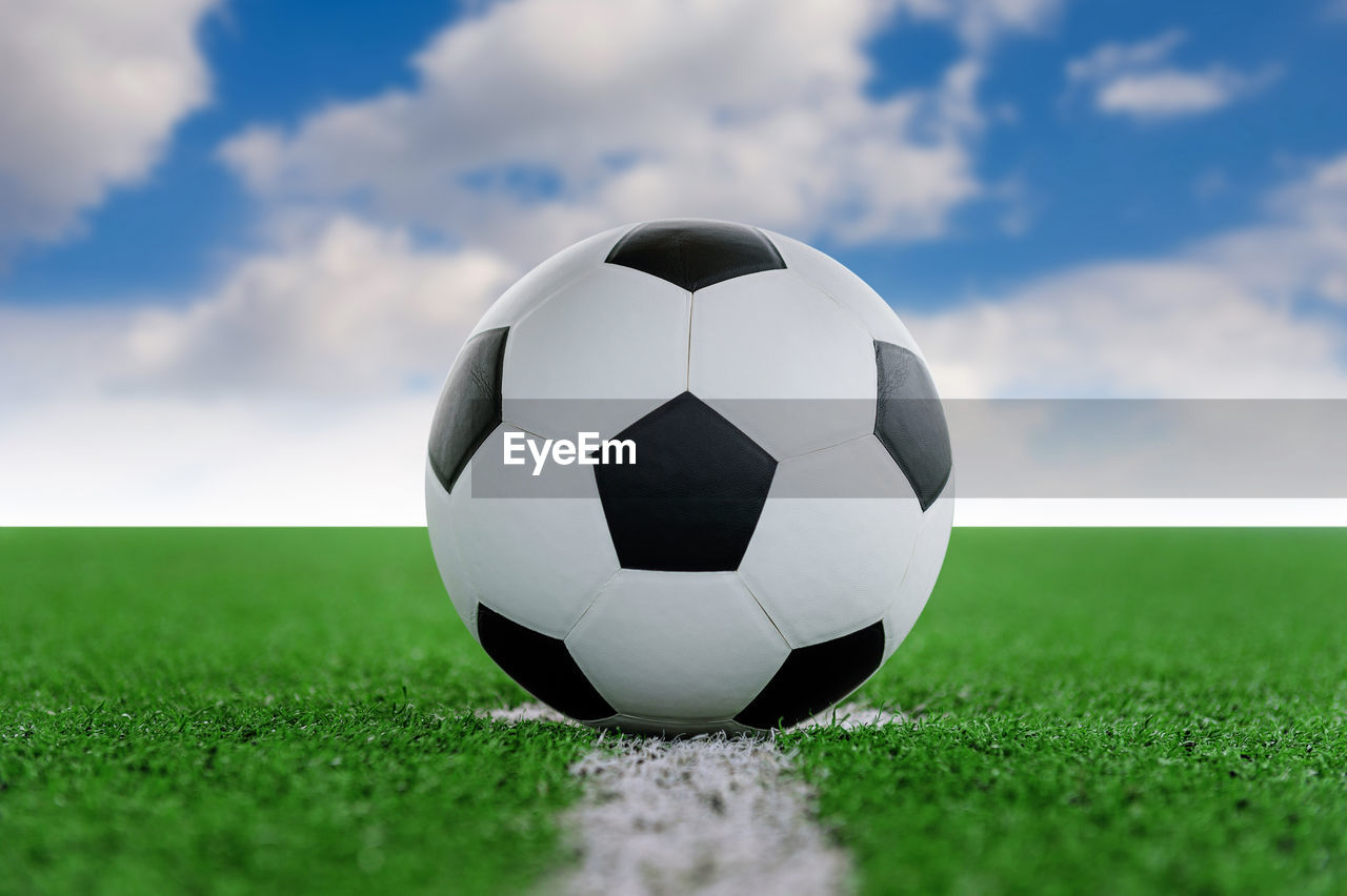 Digital composite of soccer ball on playing field against sky 