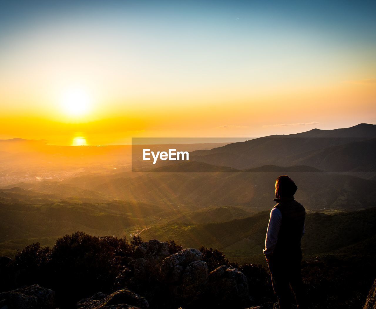 Hiker standing on mountain against sky during sunset