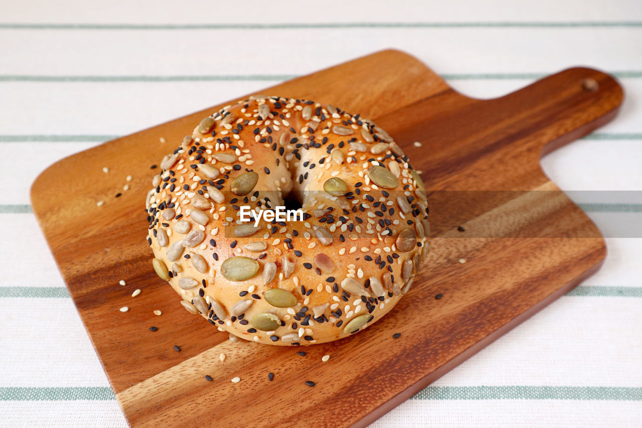 Delectable sunflower seeds and pumpkin seeds with sesame bun on wooden breadboard