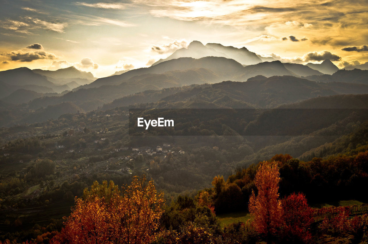 Scenic view of valley and mountains against sky during sunset