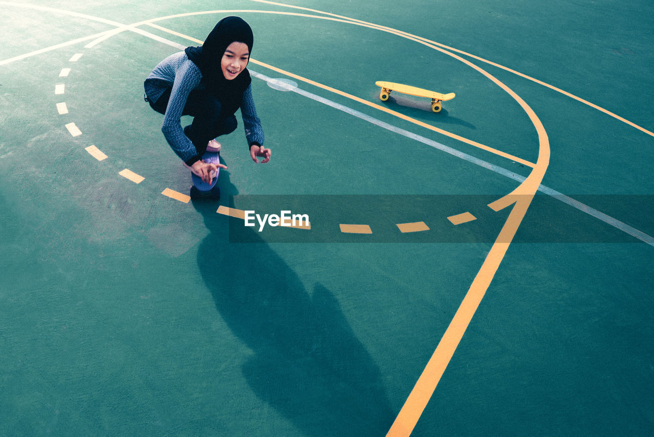 High angle view of teenage girl skateboarding at basketball court