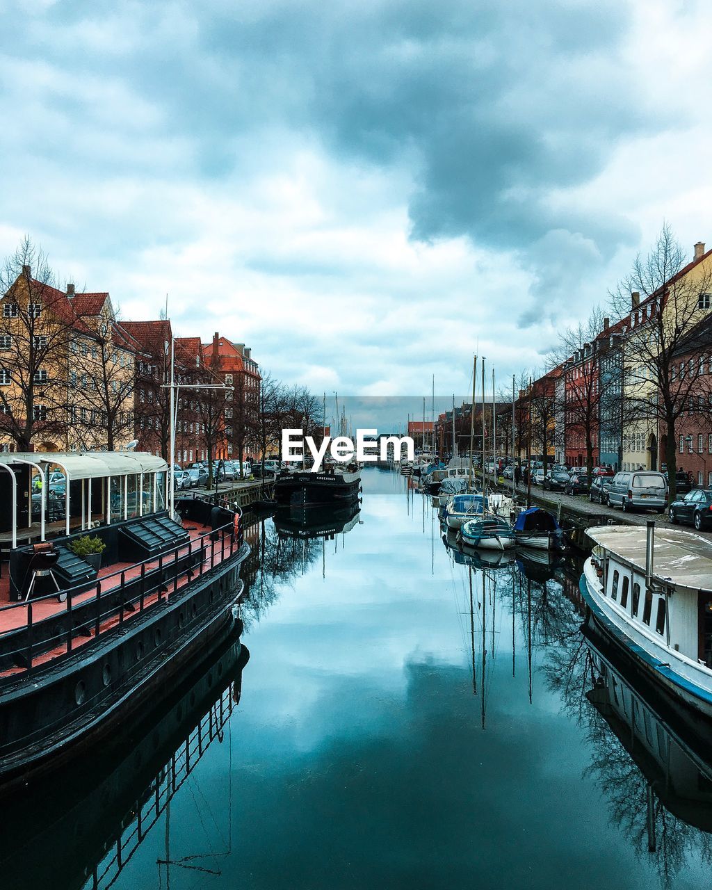 Boats moored in canal against sky in city