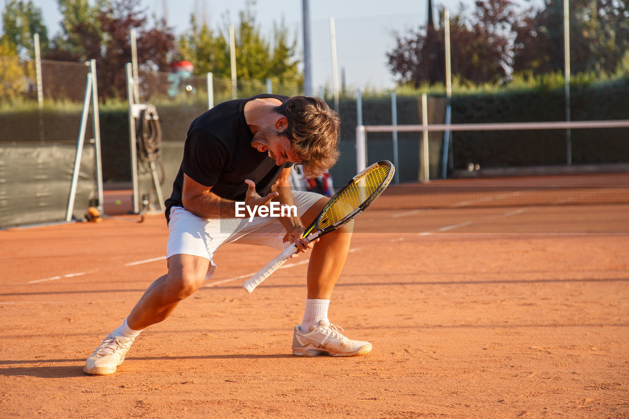 Full length of young man playing tennis on field