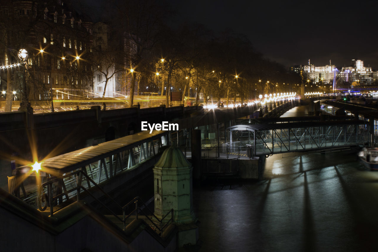 Footbridge over thames river in city at night