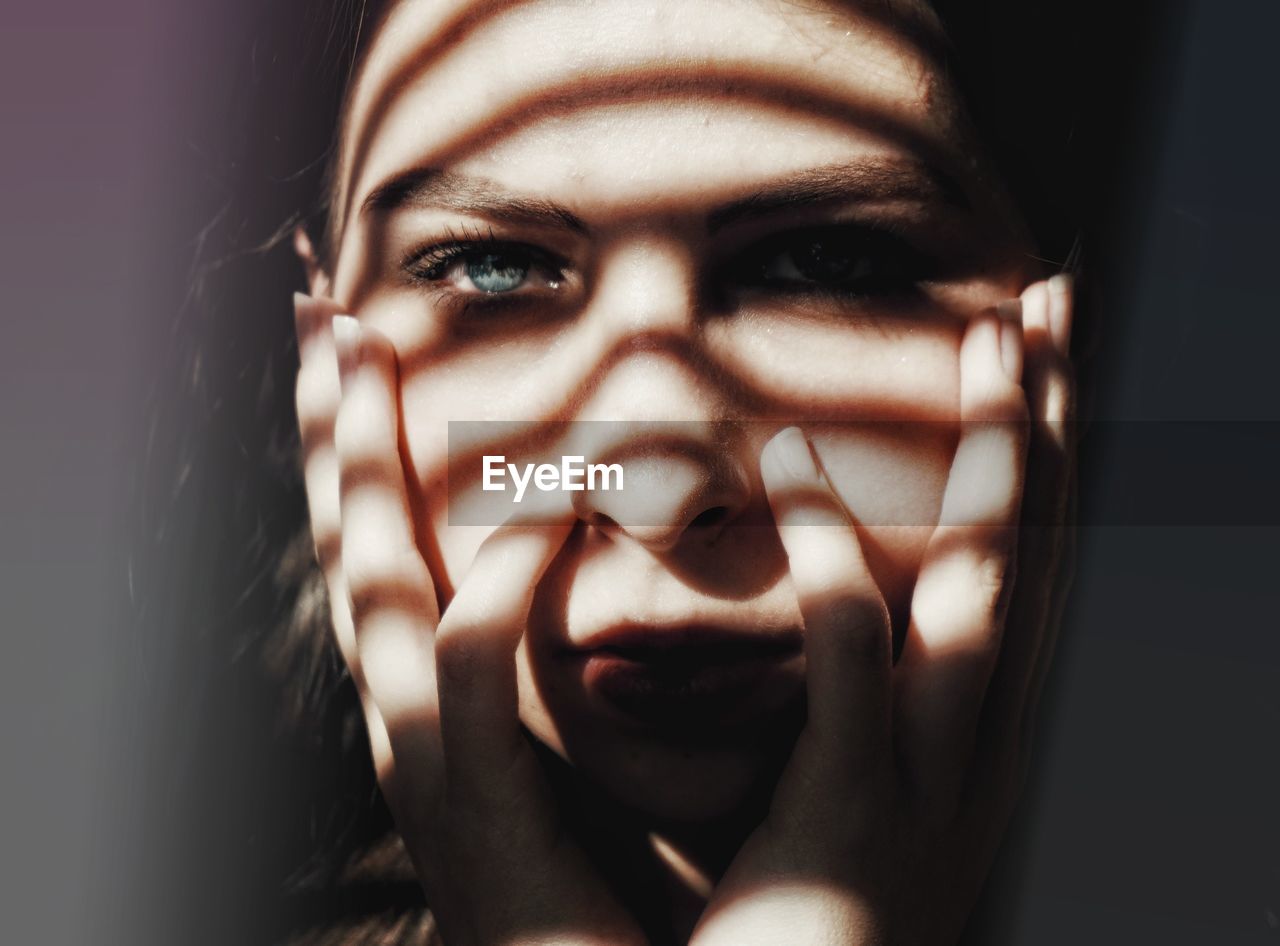 Close-up portrait of young woman with hands on chin