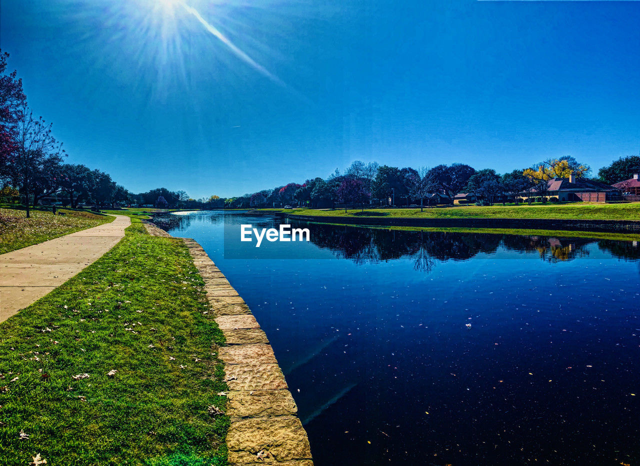 water, sky, reflection, nature, plant, lake, scenics - nature, beauty in nature, tranquility, environment, blue, tree, landscape, tranquil scene, horizon, no people, sunlight, sun, land, morning, grass, outdoors, green, sunbeam, travel destinations, clear sky, travel, lens flare, mountain, summer, idyllic, sunny, rural scene