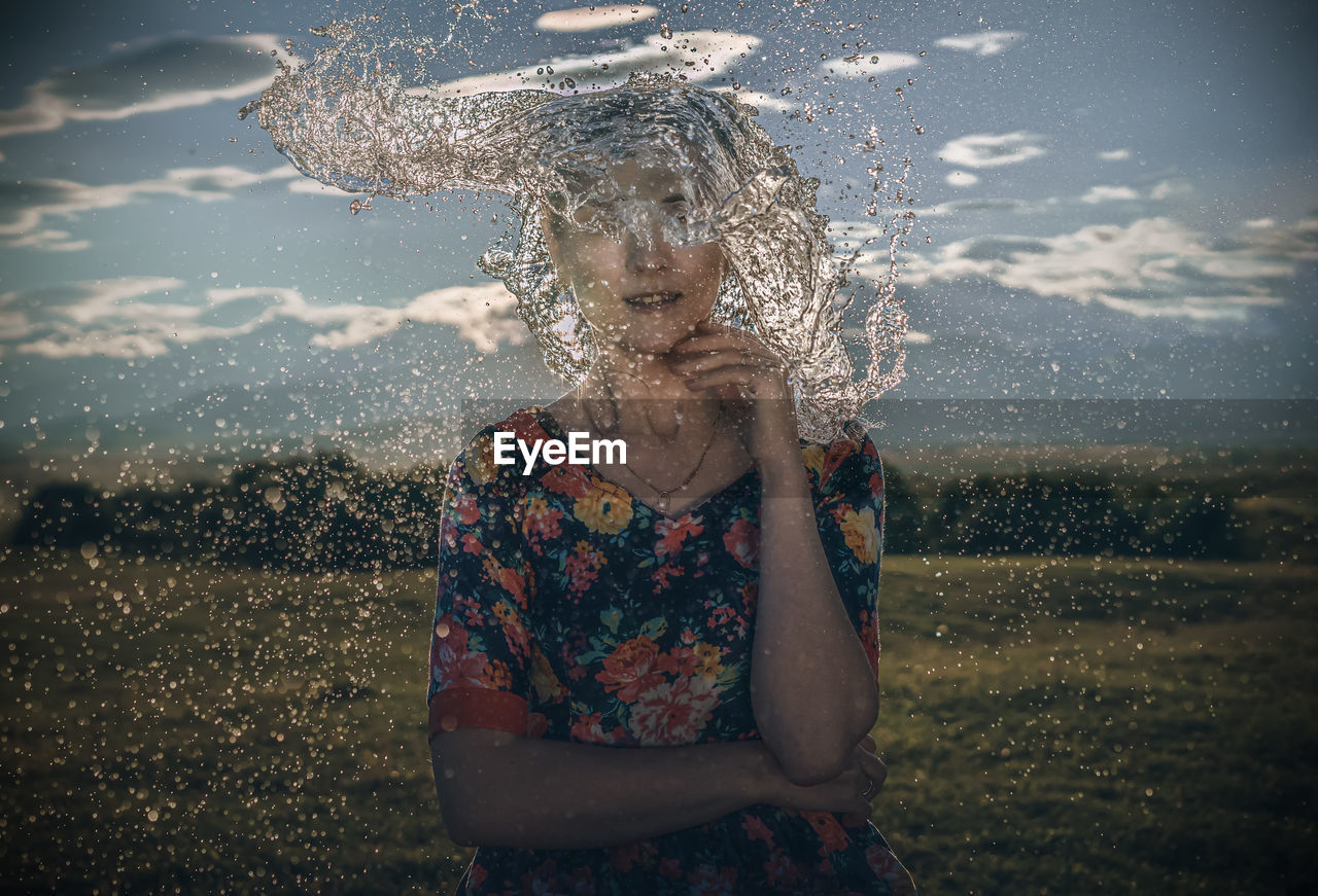 Water splashing on woman standing against sky