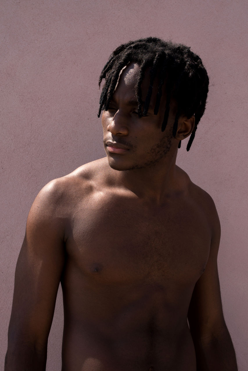 Young black man next to the pink wall portrait