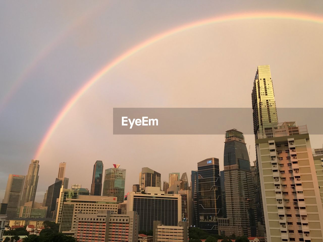 View of rainbow over cityscape against sky during sunset