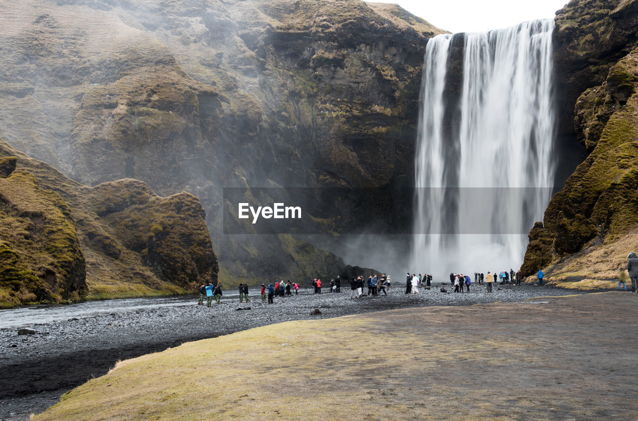 View of people on rock against waterfall