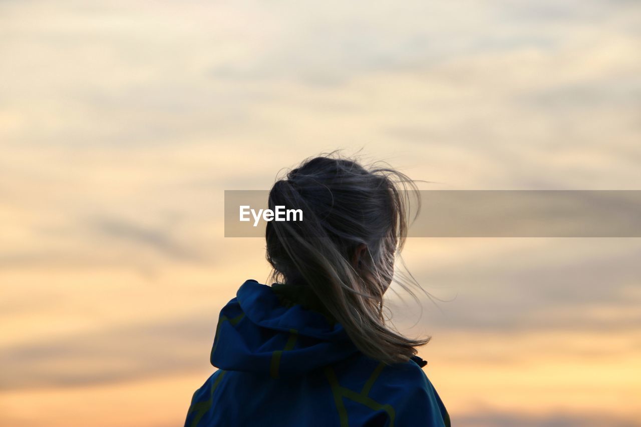 Rear view of woman against sky during sunset