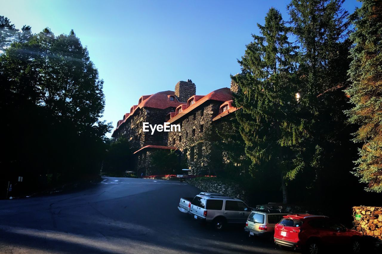 Cars on road by buildings against clear blue sky