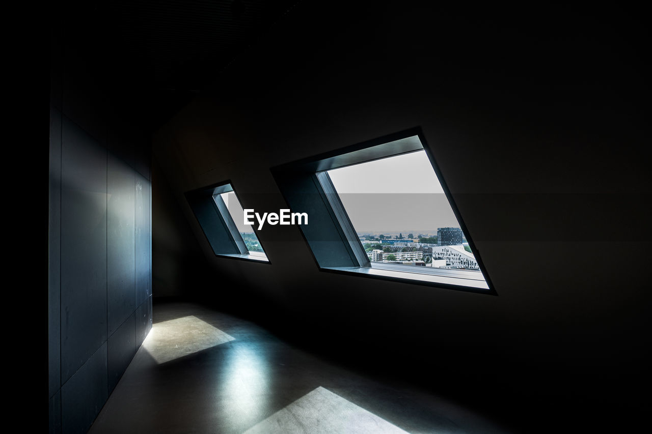 Dark room with window view over modern city