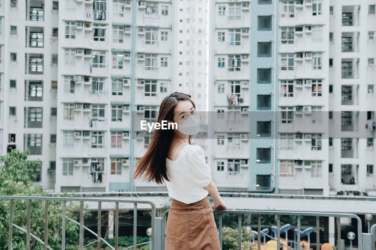 FULL LENGTH OF WOMAN STANDING AGAINST BUILDINGS