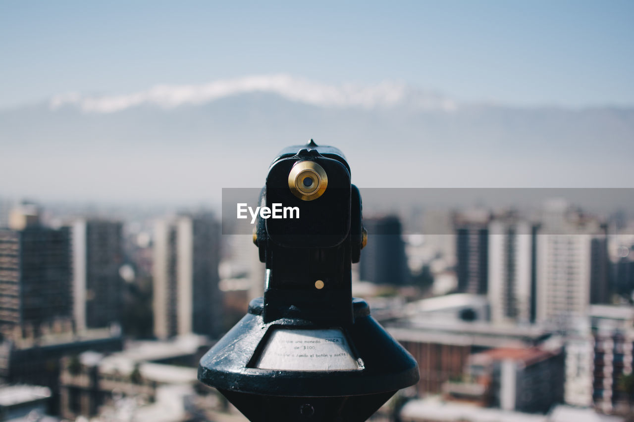 Close-up of coin-operated binoculars against city