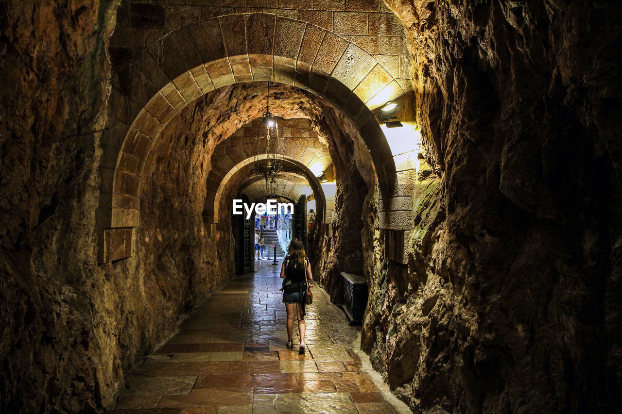 REAR VIEW OF WOMAN WALKING IN OLD BUILDING