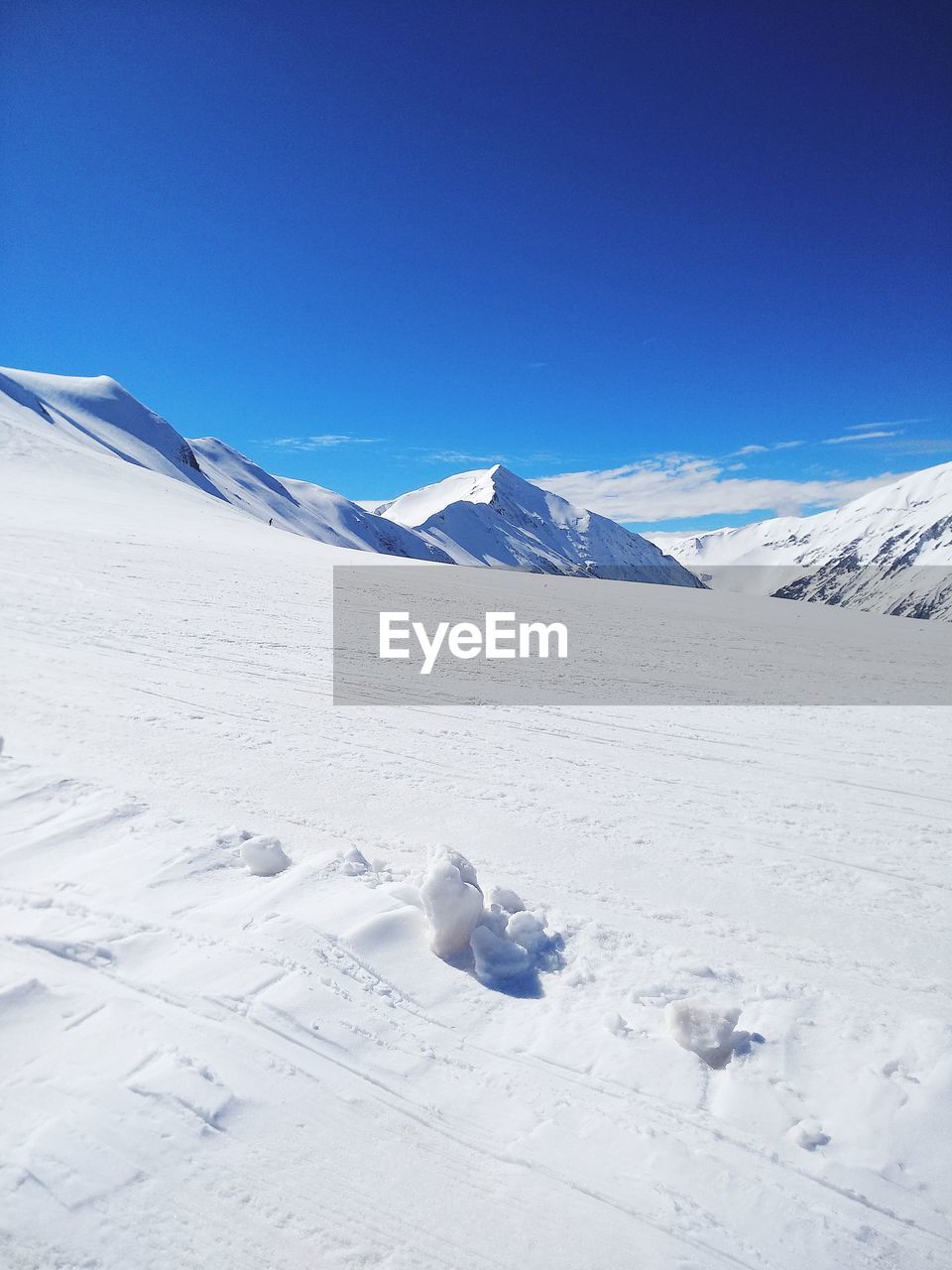 Scenic view of snowcapped mountains against blue sky