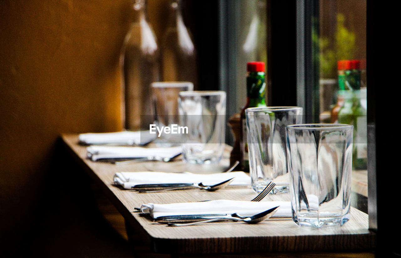 Close-up of drinking glasses with knife and folks arranged on table at restaurant