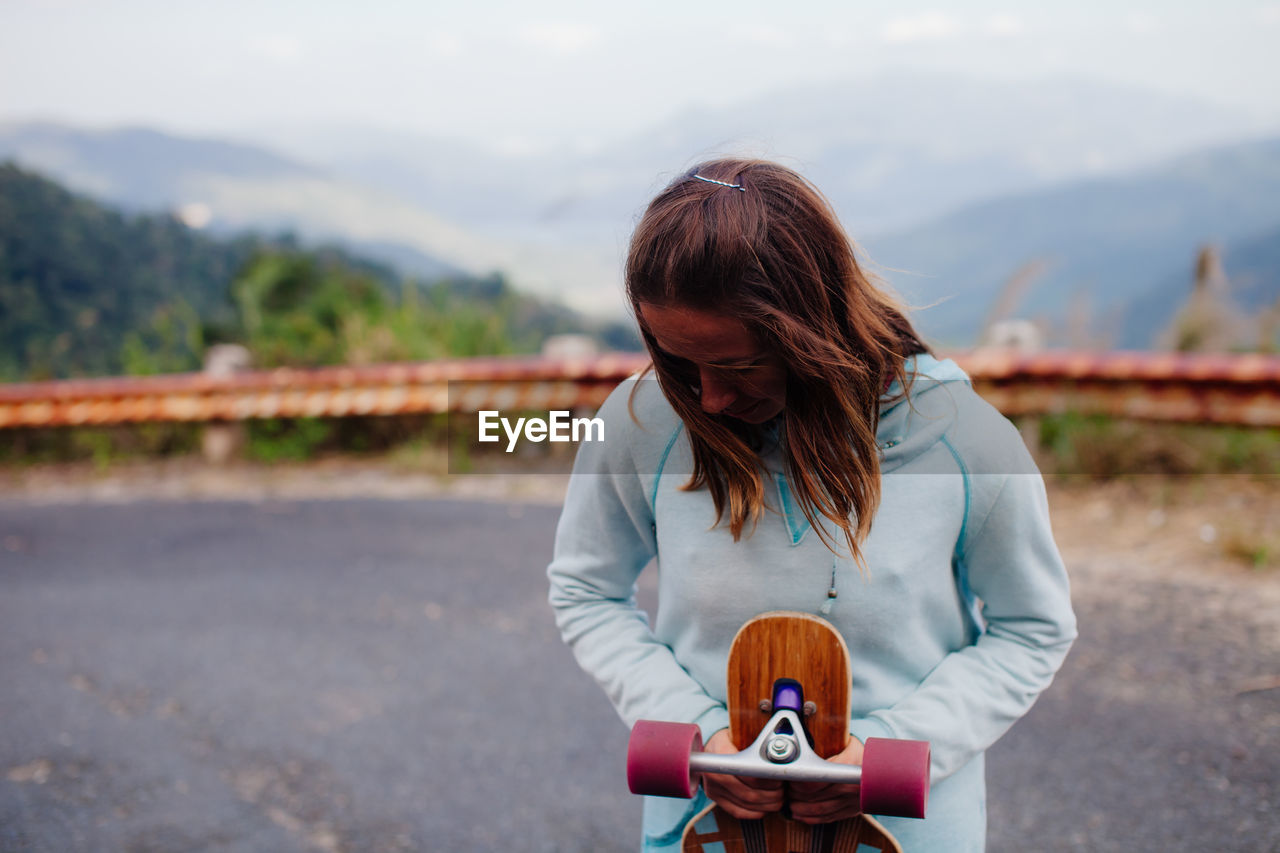 Woman with skateboard on road
