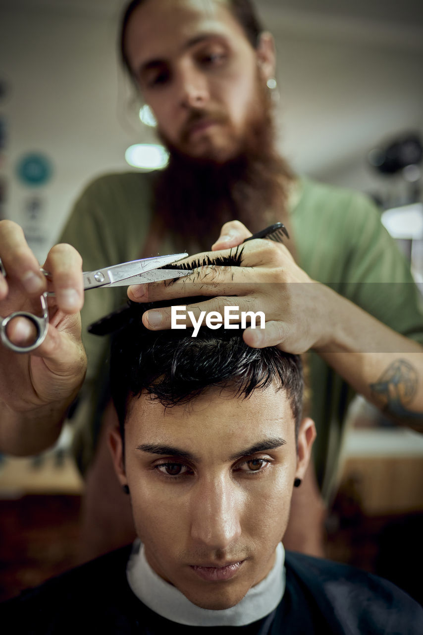 Close-up of a young man having his hair cut off