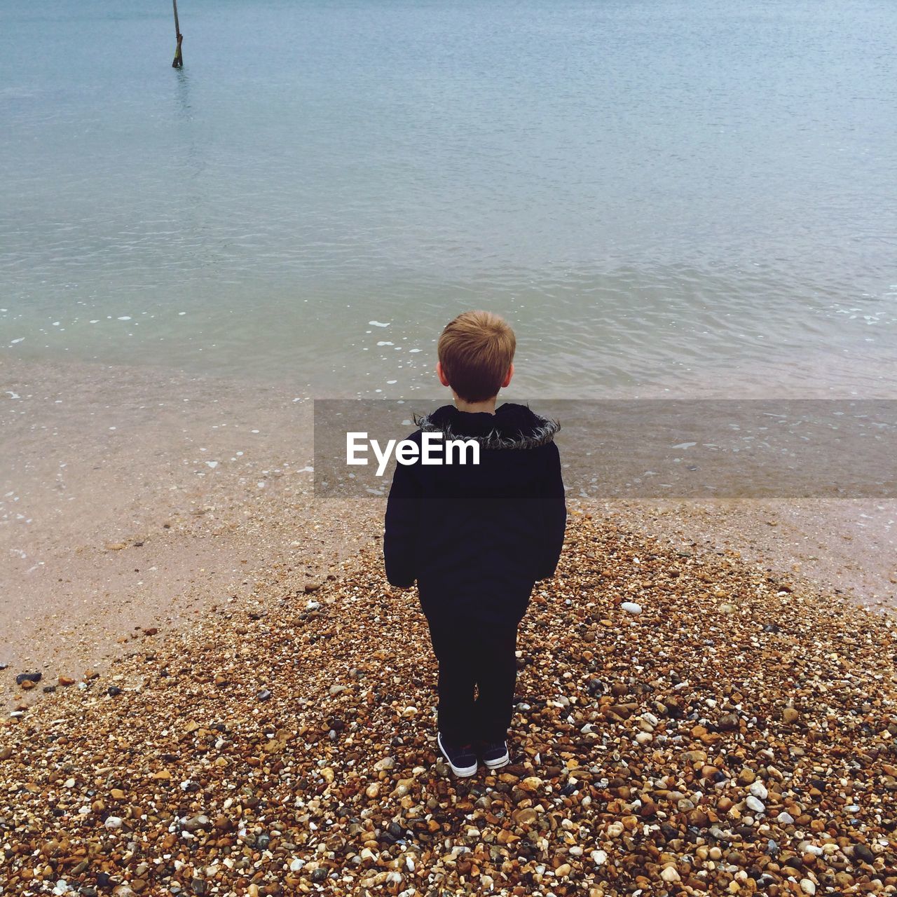 REAR VIEW OF WOMAN STANDING ON BEACH