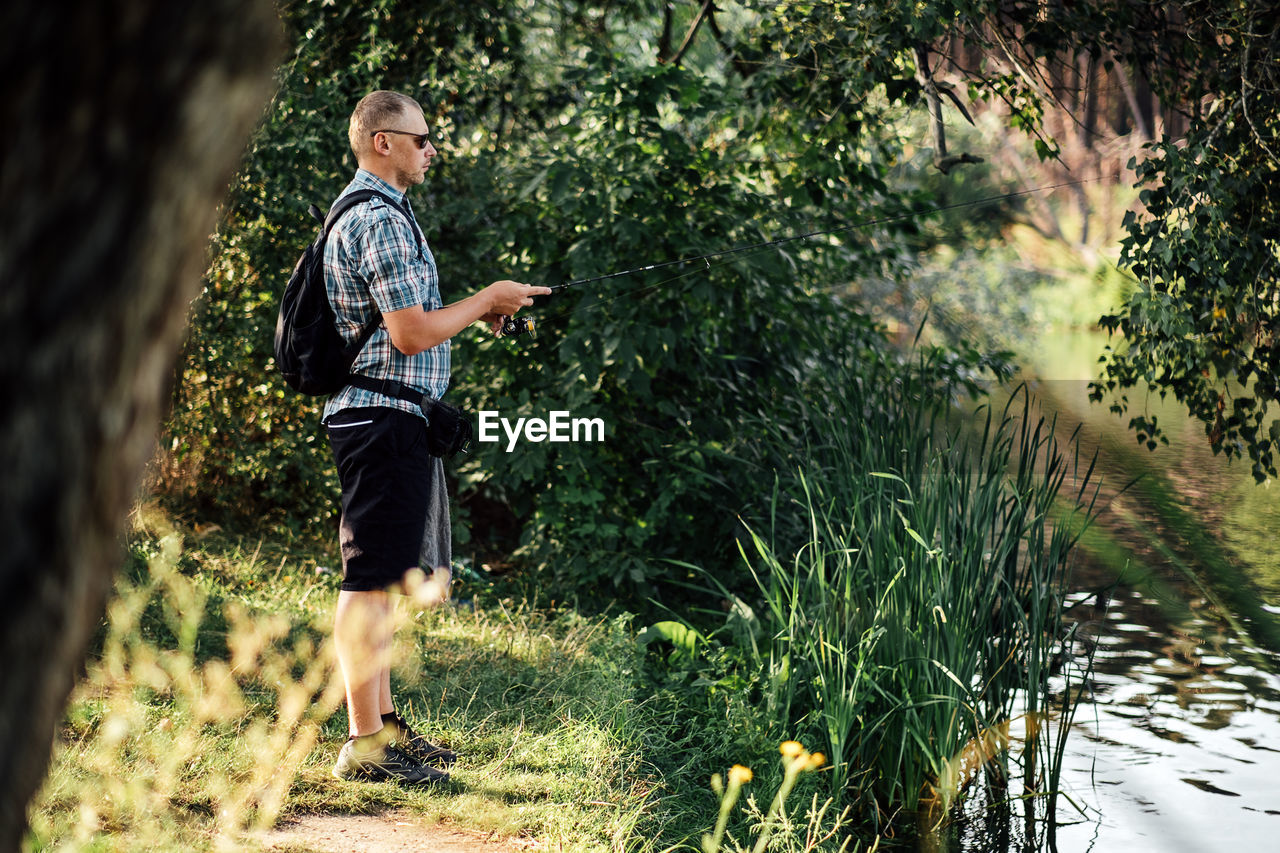 Fisherman with spinning rod on the summer lake. fisherman with spinning in his hands catching fish