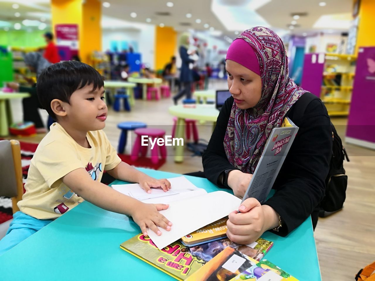 Mother and son sitting at table with books