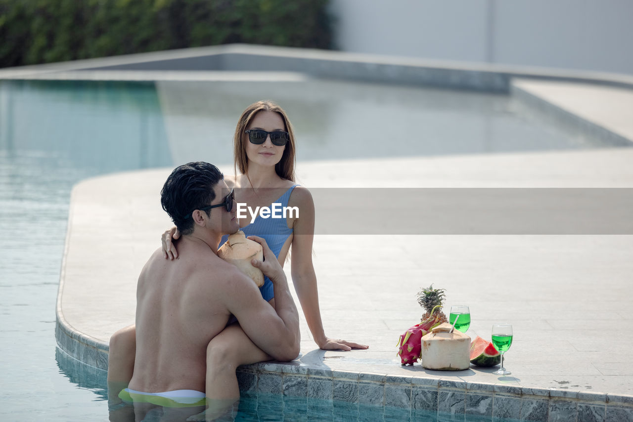 Young couple sitting on swimming pool