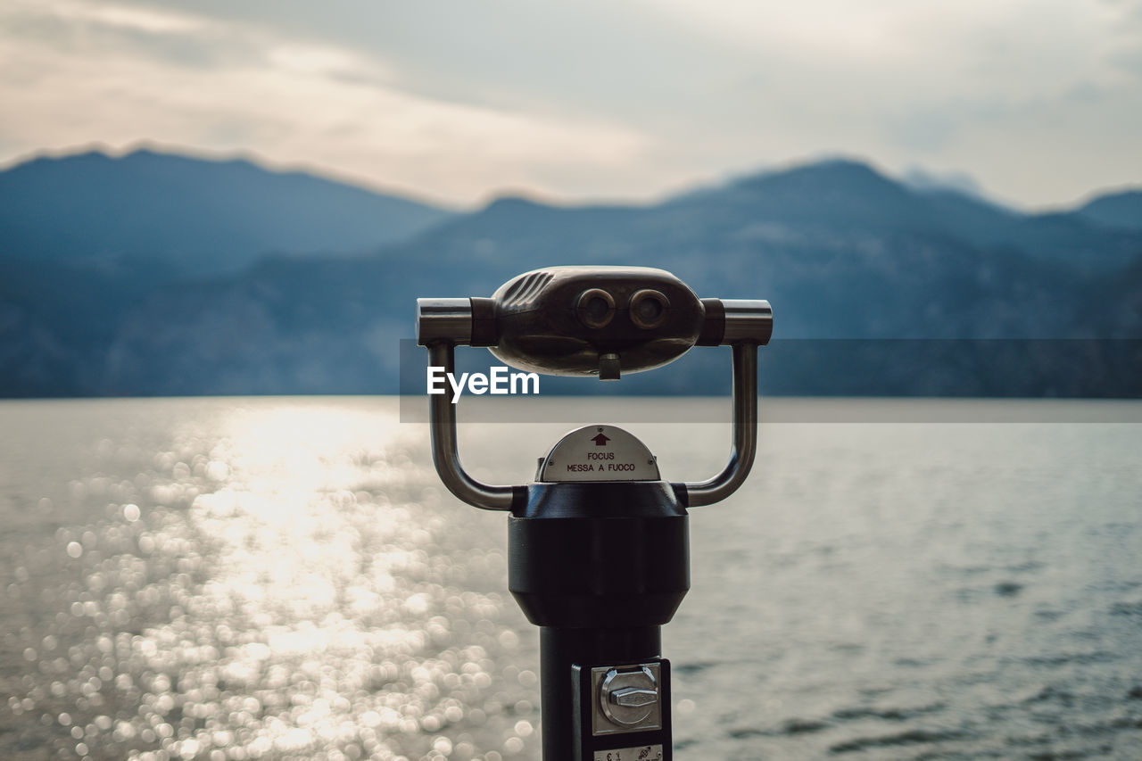 Coin-operated binoculars by sea against sky