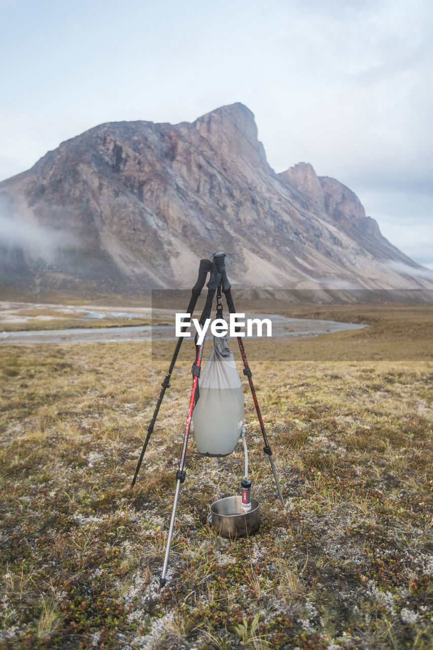 Gravity fed water filter held by tripod made with trekking poles.