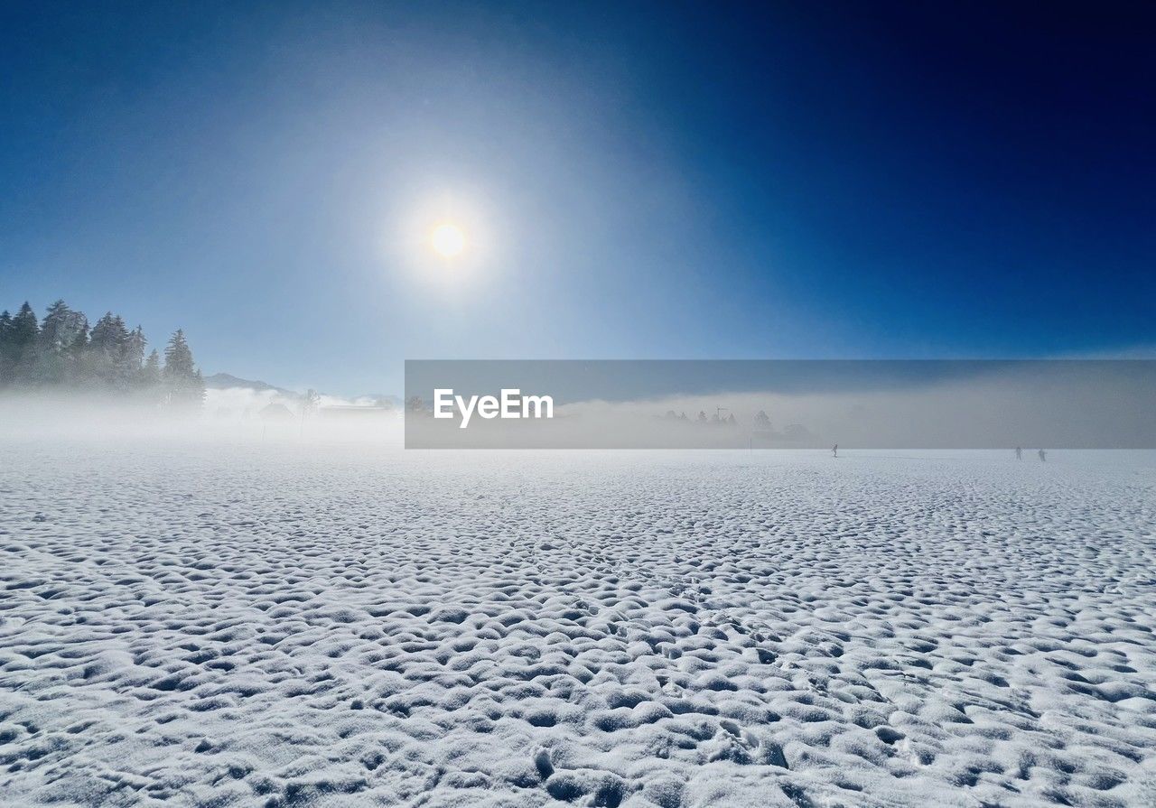 Scenic view of snow and fog against sun