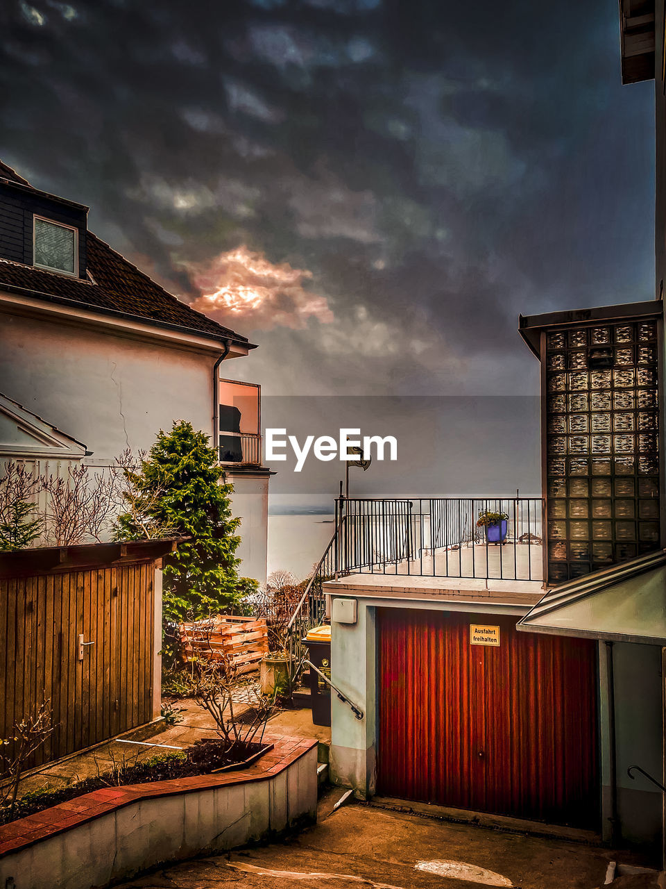 HOUSE BY BUILDING AGAINST SKY AT DUSK