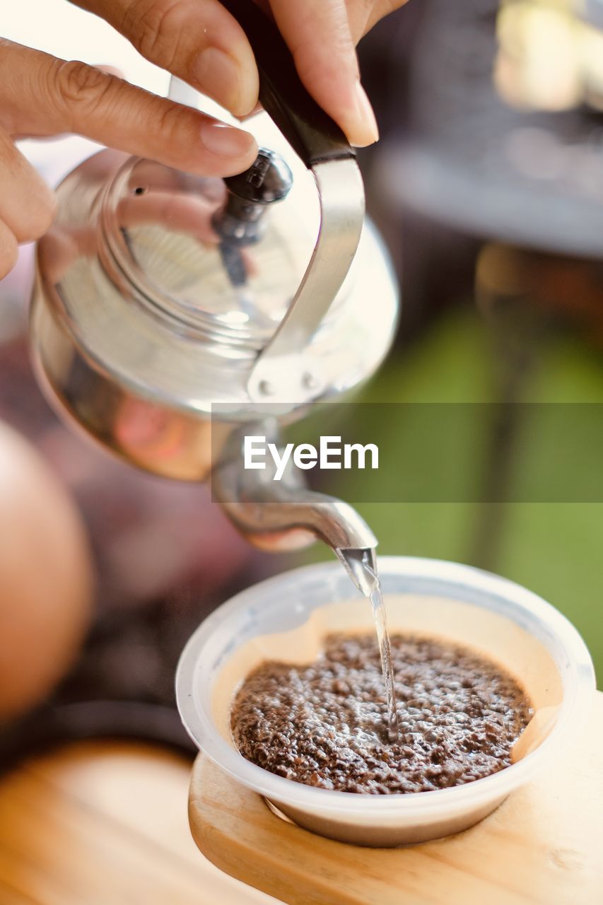 Midsection of person pouring coffee in cup