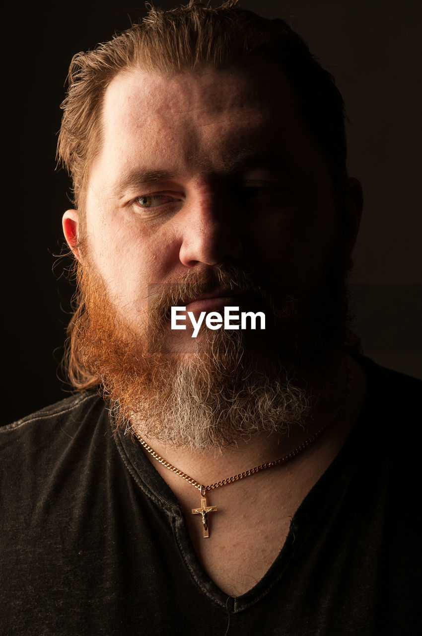 Close-up of thoughtful mid adult man against black background