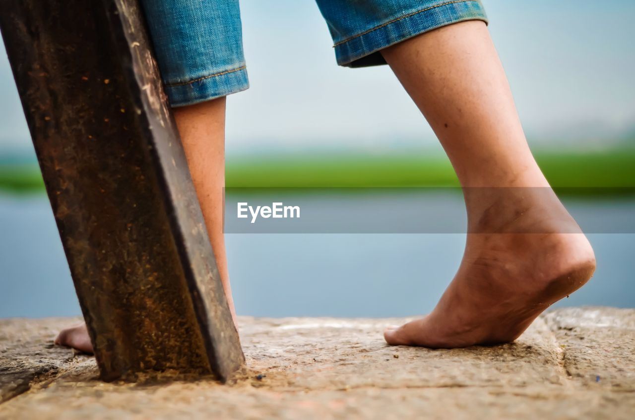 LOW SECTION OF WOMAN STANDING ON WOOD