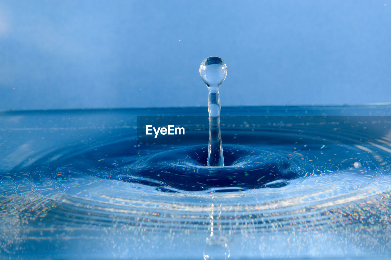Close-up of drop splashing on blue water