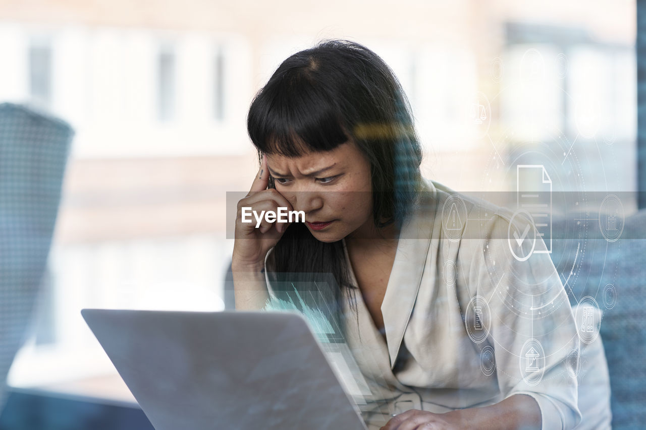 Thoughtful woman with frown forehead using laptop