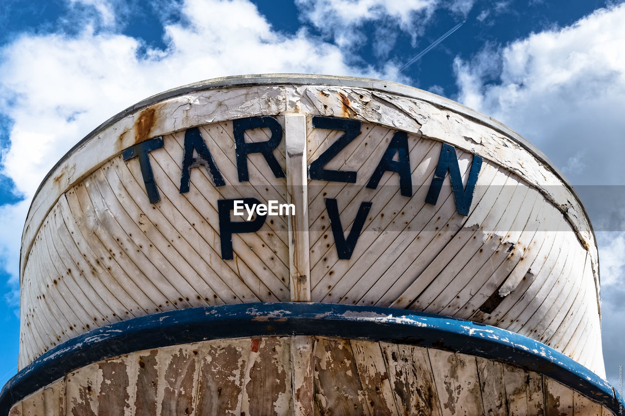 Low angle view of text on old boat against sky