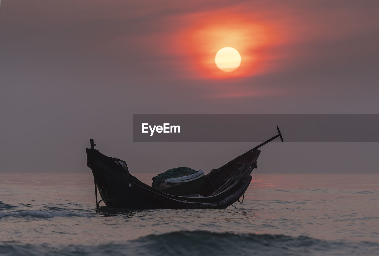 BOAT ON SEA SHORE AGAINST SKY DURING SUNSET