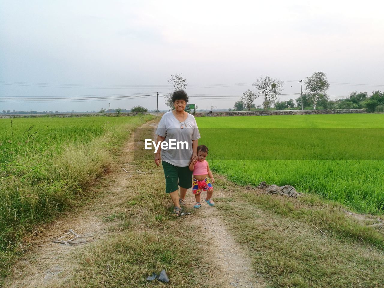 Woman walking with granddaughter on field against sky