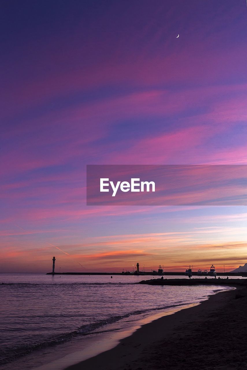 Scenic view of sea against dramatic sky during sunset