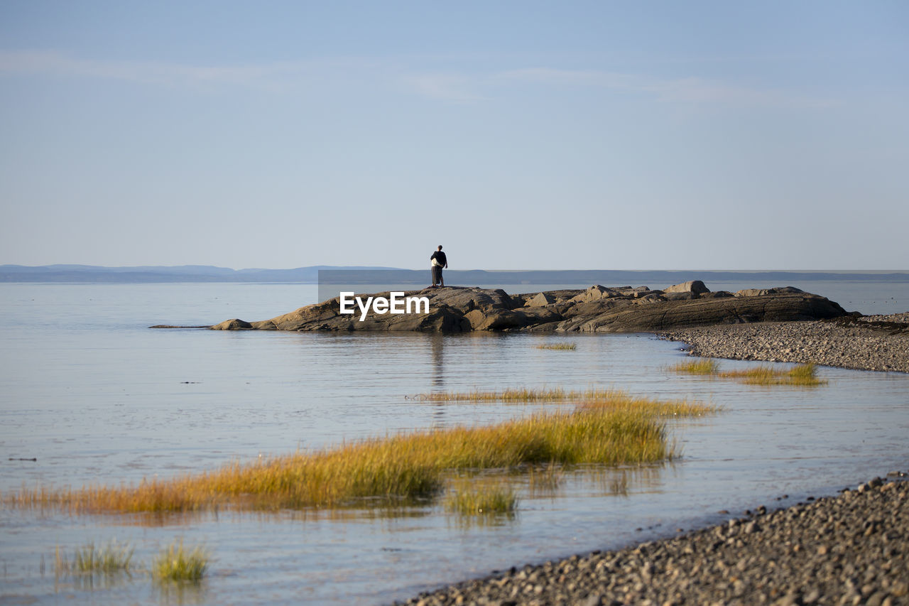 Back view of couple standing on rocks on the st. lawrence river coast looking at the view